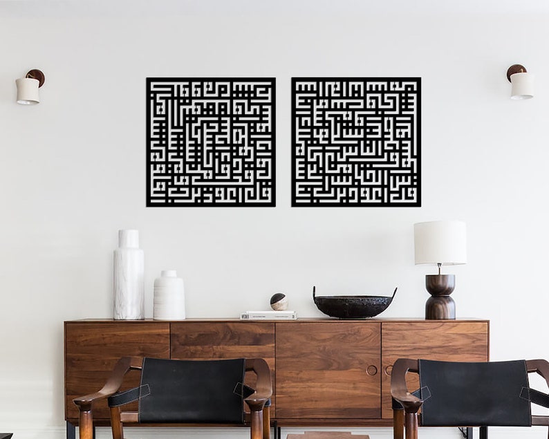 May include: Two black and white square wall art pieces with Arabic calligraphy. The art is hung on a white wall above a wooden dresser with two chairs.