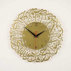 K&ouml;nnte beinhalten: Goldfarbene Wanduhr mit arabischer Kalligraphie, die das Zifferblatt umgibt. Das Zifferblatt hat schwarze Zeiger und r&ouml;mische Ziffern.