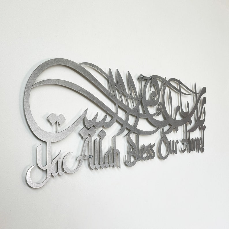 May include: A silver metal wall art piece with Arabic calligraphy and the words "Ya Allah Bless Our Home".