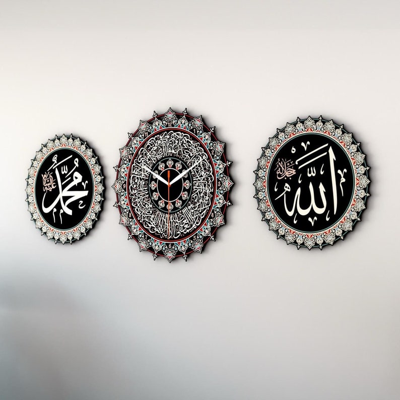 Op de afbeelding: Drie ronde wandklokken met zwarte achtergronden en ingewikkelde witte ontwerpen. De klok in het midden heeft een witte wijzerplaat met zwarte wijzers en Arabische cijfers. De klok links toont het Arabische woord "Muhammad" in wit. De klok rechts toont het Arabische woord "Allah" in wit.