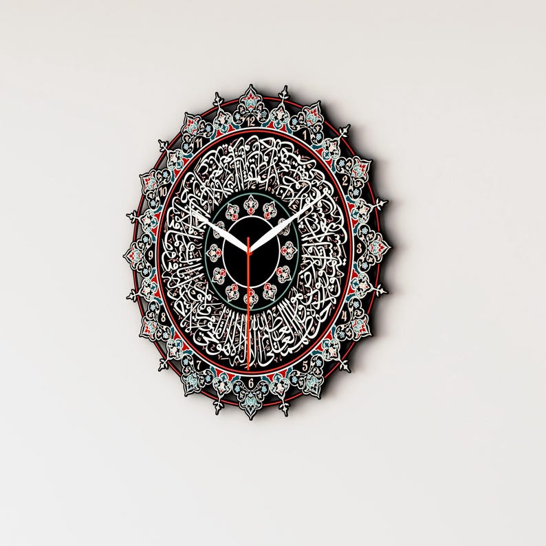 Op de afbeelding: Een ronde wandklok met Arabische kalligrafie en ingewikkelde ontwerpen in rood, blauw en groen. De wijzerplaat van de klok is zwart met witte cijfers en wijzers.