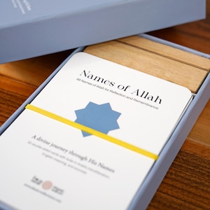 K&ouml;nnte beinhalten: Ein hellblaues Box-Set mit einem Kartenspiel mit dem Titel "Namen Allahs". Die Karten werden mit einem gelben Gummiband zusammengehalten. Der Text auf den Karten lautet "99 Namen Allahs f&uuml;r Reflexion und Erinnerung".