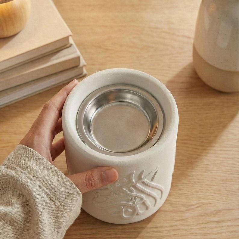 Peut inclure: Un diffuseur d'huiles essentielles en c&eacute;ramique blanche avec un r&eacute;cipient en m&eacute;tal argent&eacute;. Le diffuseur a une forme cylindrique avec un motif en relief. Un objet de d&eacute;coration pour l'aromath&eacute;rapie.