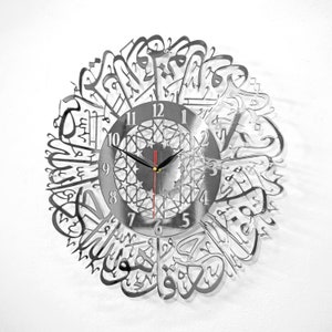 May include: A silver metal wall clock with Arabic calligraphy around the face. The clock face has a black background with white numbers and a silver, geometric design in the center. The clock hands are black and red.