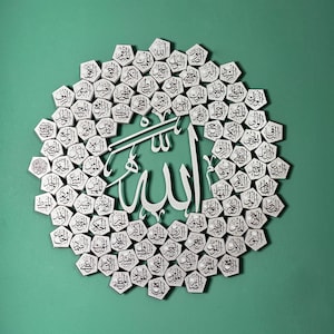 Peut inclure: Une &oelig;uvre d'art islamique blanche et argent&eacute;e avec le mot "Allah" en calligraphie arabe entour&eacute; d'un cercle de plus petites tuiles blanches et argent&eacute;es avec du texte arabe.
