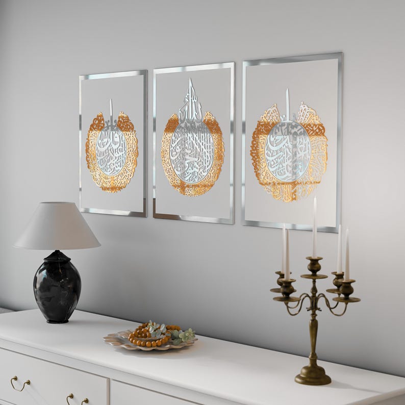 May include: Three framed wall art pieces with silver frames and gold calligraphy inside. The calligraphy is in Arabic script and is surrounded by a decorative border.