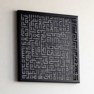 May include: A black metal wall art piece with a geometric design featuring a repeating pattern of squares and rectangles. The design is cut out of the metal, creating a shadow effect.