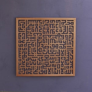 May include: A square metal wall decor with a intricate design of Arabic calligraphy cut out in the metal. The design is in a copper color and the background is a dark gray.