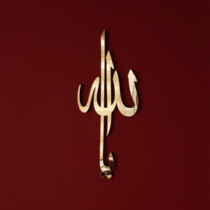 May include: Gold-coloured metal wall decor in the shape of the Arabic word "Allah" on a red background.