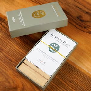 K&ouml;nnte beinhalten: Ein offenes, hellgr&uuml;nes Box-Set mit einem Kartenspiel "Prophetic Duas". Die Karten sind wei&szlig; mit gelben Akzenten und Text in Englisch und Arabisch. Die Box enth&auml;lt auch Holzteiler. Die Box steht auf einer Holzoberfl&auml;che.