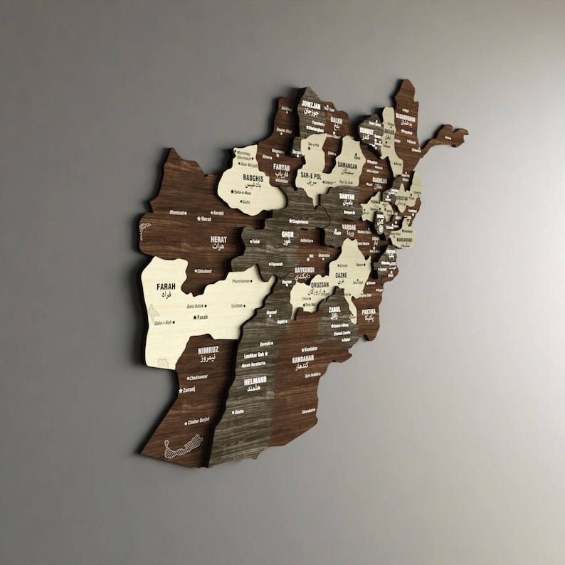 May include: A wooden map of Afghanistan with the names of each province in English and the local language. The map is made of different shades of brown wood and is mounted on a gray wall.