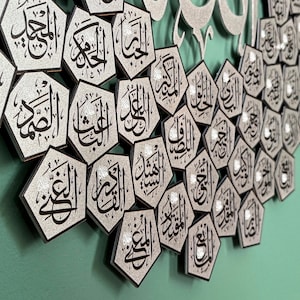 Peut inclure: Une &oelig;uvre d'art murale islamique argent&eacute;e et noire avec un motif d&eacute;coratif de multiples formes hexagonales avec de la calligraphie arabe. Les formes sont dispos&eacute;es en un motif semi-circulaire.