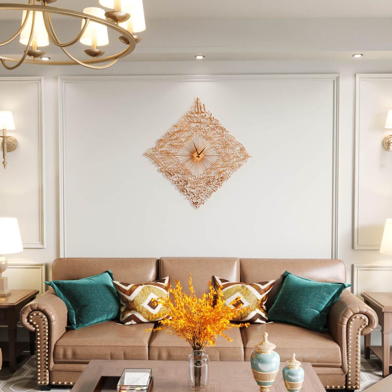 May include: A decorative wall clock with a diamond-shaped design and intricate cut-out patterns. The clock is made of a copper-colored metal and features a central clock face with hands. The clock hangs above a brown leather sofa with teal and patterned pillows.