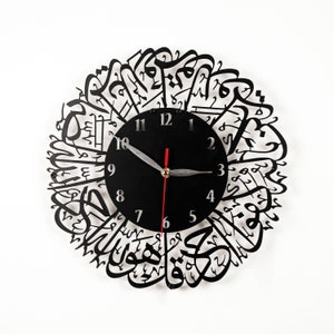 May include: Black wall clock with Arabic calligraphy surrounding the clock face. The clock face has black hands and white numbers.