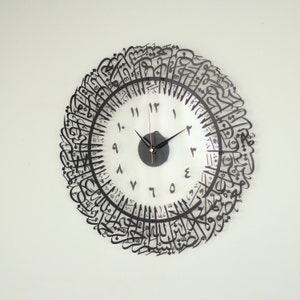 May include: A black and white clock with Arabic calligraphy around the edge. The clock face has black Roman numerals and black hands.