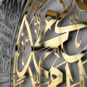 May include: A gold-colored metal wall decor with intricate Arabic calligraphy. The design is cut out of the metal, creating a shadow effect.