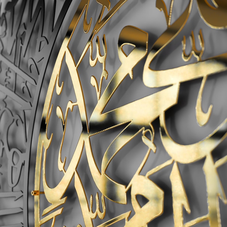 May include: A gold-colored metal wall decor with intricate Arabic calligraphy. The design is cut out of the metal, creating a shadow effect.