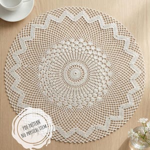 May include: A cream-colored, circular crochet doily with a detailed geometric pattern. The doily features a central circular design and a zigzag border. A white teacup and saucer are in the upper left corner. The text "PDF PATTERN NO PHYSICAL ITEM" is in the lower left.