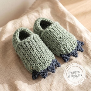 Könnte beinhalten: Ein Paar gestrickte Babyschuhe in einem sanften Grünton, mit dunkelblauer Verzierung an der Spitze. Die Babyschuhe sind handgefertigt und liegen auf einem neutralfarbenen Stoff. Der Text "PDF PATTERN NO PHYSICAL ITEM" ist sichtbar.