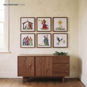 May include: Six square framed cross-stitch artworks featuring religious scenes, including a nativity, an angel, a star, three kings, a shepherd with a lamb, and a dove. The text WILLOWHOMESTUDIO appears in the top left corner.
