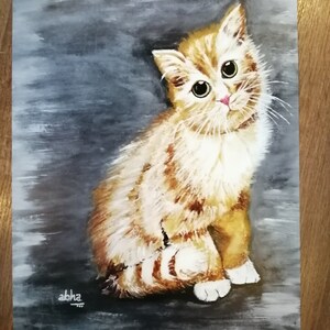 May include: A watercolor painting of a ginger kitten with green eyes, sitting on a gray background. The kitten is looking up and to the right, with its tail curled around its body. The painting is signed "abha" in the bottom left corner.