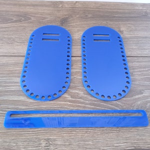 Könnte beinhalten: Drei hellblaue Acryl-Taschenböden und ein Griffstück. Die ovalen Böden haben eine Reihe von Löchern am Rand zum Nähen. Jeder Boden hat zwei parallele Schlitze oben. Das Griffstück ist ein langes, dünnes Rechteck mit einem Schlitz.