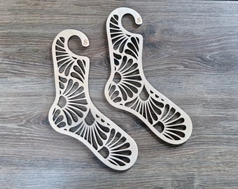 Könnte beinhalten: Zwei Sockenhalter aus Holz mit einem dekorativen Blumenmuster. Die Halter sind sockenförmig und haben oben einen Haken.