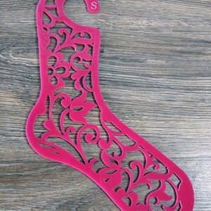 Può includere: Un espositore per calzini in plastica rosa con un design floreale e un gancio nella parte superiore. L'espositore è etichettato con la lettera "S".