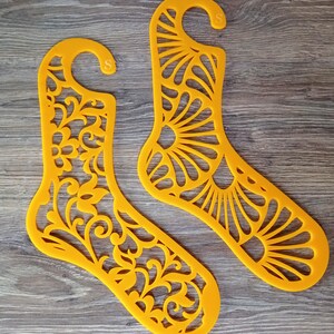 Può includere: Due organizzatori per calzini in plastica gialla con un design decorativo tagliato. Gli organizzatori hanno un gancio nella parte superiore per appendere.