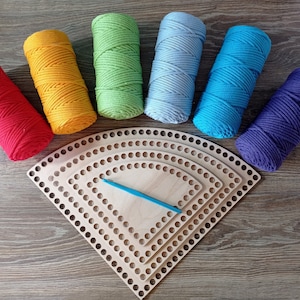 May include: A set of six colourful cotton cords and three wooden crochet hoops. The cords are red, orange, green, blue, light blue, and purple. The hoops are nested inside each other and are made of natural wood.