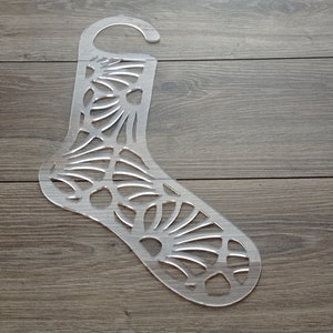 Op de afbeelding: Een transparante sokkenvorm van plastic met een decoratief patroon. De vorm heeft een haak aan de bovenkant om op te hangen.