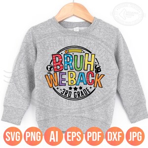 May include: A gray sweatshirt with the text "BRUH WE BACK 3RD GRADE" in a colorful, circular design. The design includes a pencil, globe, backpack, and stars. The sweatshirt is displayed on a wooden hanger.