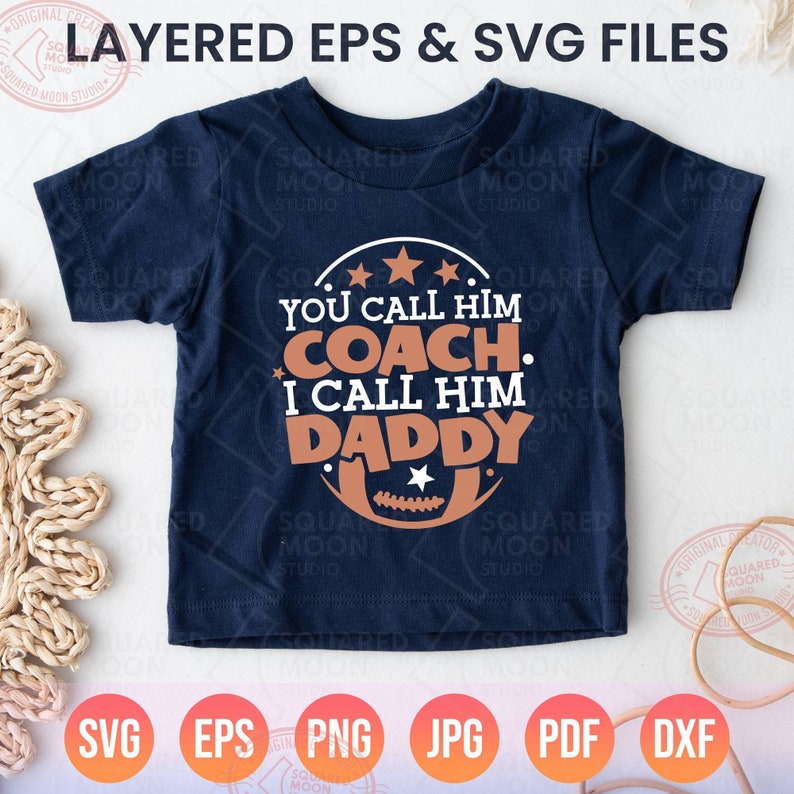 May include: A navy blue t-shirt with a white and brown graphic design. The graphic features a football and the text "You call him coach. I call him daddy."