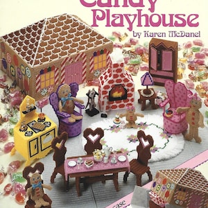 May include: A plastic canvas craft pattern book titled Candy Playhouse by Karen McDanel, featuring a gingerbread-style house, furniture, and gingerbread figures. The cover displays a completed set with a fireplace, table, chairs, and accessories.