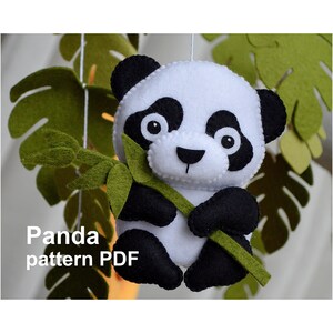 Könnte beinhalten: Ein Filz-Pandabär, der einen grünen Bambusstab hält. Der Panda ist weiß mit schwarzen Ohren, Augen, Nase und Pfoten. Der Text "Panda pattern PDF" befindet sich unter dem Panda.
