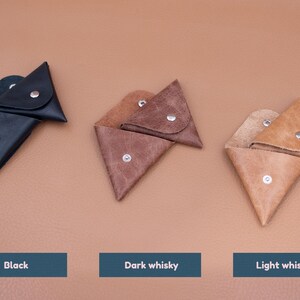 May include: Three leather coin purses in black, dark whisky, and light whisky colors. Each triangular pouch has a snap closure. The text below each purse reads "Black", "Dark whisky", and "Light whisky".
