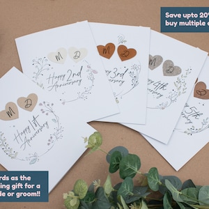 K&ouml;nnte beinhalten: Satz von f&uuml;nf wei&szlig;en Karten mit einem floralen Design und braunen herzf&ouml;rmigen Verzierungen. Jede Karte zeigt eine andere Jubil&auml;umszahl von 1. bis 5. Der Text "Happy [Jubil&auml;umszahl] Anniversary" ist auf jeder Karte gedruckt.