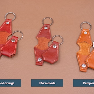 May include: Three leather keychains in blood orange, marmalade, and pumpkin colors. Each keychain features a metal ring and a snap-button closure. The text labels below each item read Blood orange, Marmalade, and Pumpkin respectively.