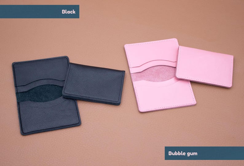 May include: Two leather card holders, one black and one pink. The black card holder has a suede interior. The pink card holder has a white interior. The text "Black" is above the black card holder and the text "Bubble gum" is below the pink card holder.