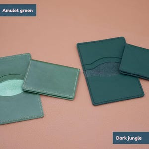 May include: Two leather card holders in different shades of green. The card holder on the left is a lighter shade of green called "Amulet green". The card holder on the right is a darker shade of green called "Dark jungle".