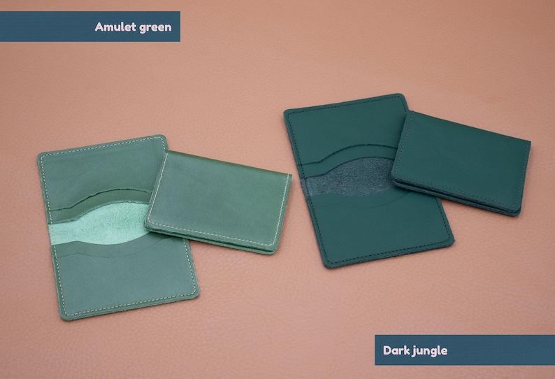 May include: Two leather card holders in different shades of green. The card holder on the left is a lighter shade of green called "Amulet green". The card holder on the right is a darker shade of green called "Dark jungle".