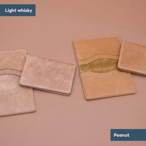 May include: Four leather wallets in two different colors. Two wallets are light brown and two are a lighter shade of brown. The wallets are all closed and have a stitched edge. The text "Light whisky" is at the top of the image and the text "Peanut" is at the bottom of the image.