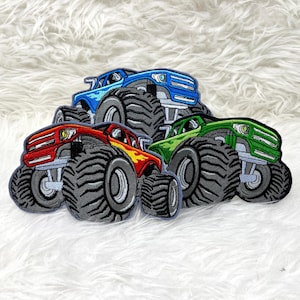 Könnte beinhalten: Vier Monstertruck-Patches, einer rot, einer blau, einer grün und einer schwarz. Jeder Patch zeigt einen Monstertruck mit großen Reifen und einem detaillierten Design.