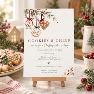 Pode incluir: Um cartão de convite retangular num cavalete de madeira com ilustrações em aguarela de bolachas de gengibre penduradas, ramos de pinheiro e bagas vermelhas. O texto diz: COOKIES & CHEER, Join us for a Christmas cookie exchange, Saturday, December 12, 2026, 2:00-5:00 PM, The Hartwell Home, 42 Pine Lane, Willowbrook, Bring 3 dozen cookies to share, RSVP by December 1, hello@example.com.
