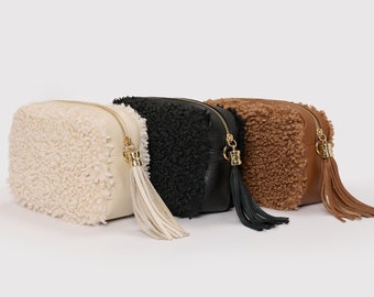 Könnte beinhalten: Drei kleine, runde, Reißverschlusstaschen mit flauschigem, Kunstfell-Außenmaterial. Die Taschen sind in Weiß, Schwarz und Braun.