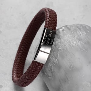 May include: A dark maroon braided bracelet featuring a polished silver-tone rectangular metal clasp. The clasp is engraved with the text "Don't let the hard days win" in a clean, sans-serif font. The bracelet has a woven texture throughout.