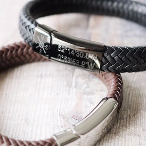 May include: Two leather bracelets with metal clasps. The black bracelet has coordinates engraved on the clasp: 52°14'30.8"N 0°53'53.9"W.
