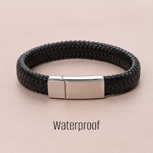 Op de afbeelding: Een zwarte gevlochten leren armband met een zilveren magneetsluiting. Waterdicht.