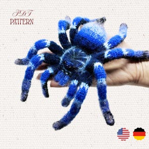 May include: A handmade blue and black crocheted spider with white accents. The spider has eight legs and a round body. The text "PDF PATTERN" is in the upper left corner.
