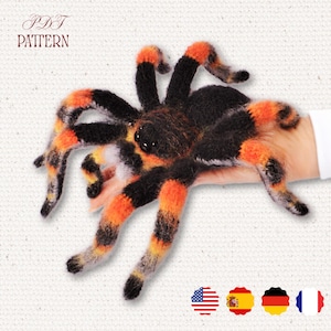 May include: A handmade, plush spider with black, orange, and yellow striped legs and body. The spider is held in a hand. The text "PDF PATTERN" is in the upper left corner.